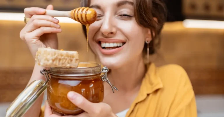 A smiling woman with a jar of honey in her hand